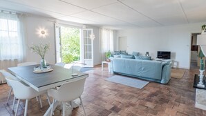 Ein geräumiger Wohnbereich mit Esstisch, Stühlen, einer Couch und einem Fernseher.