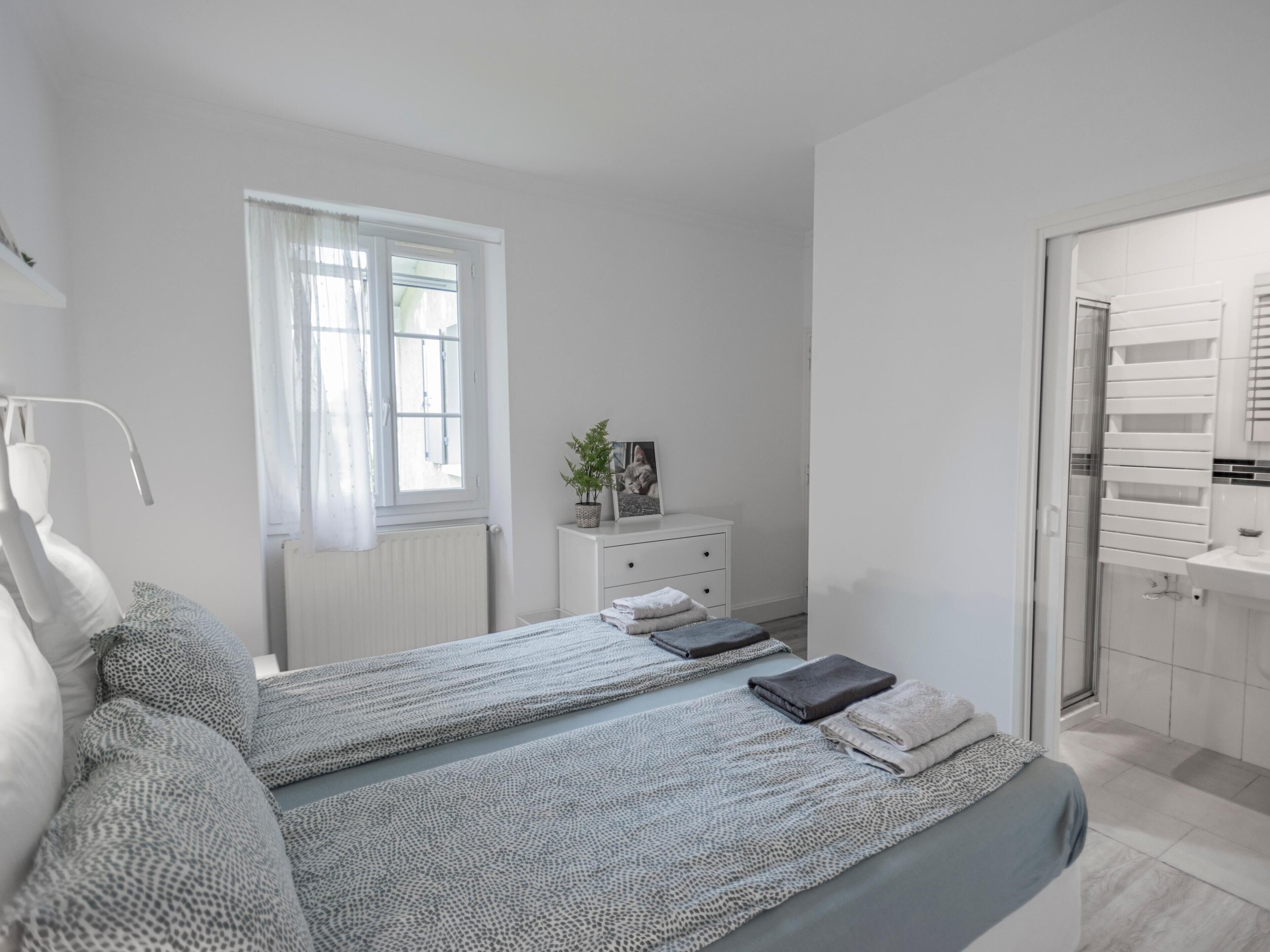 Une chambre à coucher moderne avec un grand lit, une table de chevet agrémentée d’une plante et une vue sur la salle de bain.
