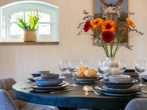 A beautifully set table with a view, featuring fine china, glasses, and a vase with fresh flowers.