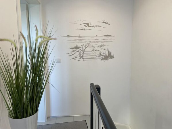 A hallway with a wall mural depicting a landscape scene with a path leading to a body of water and distant landforms.