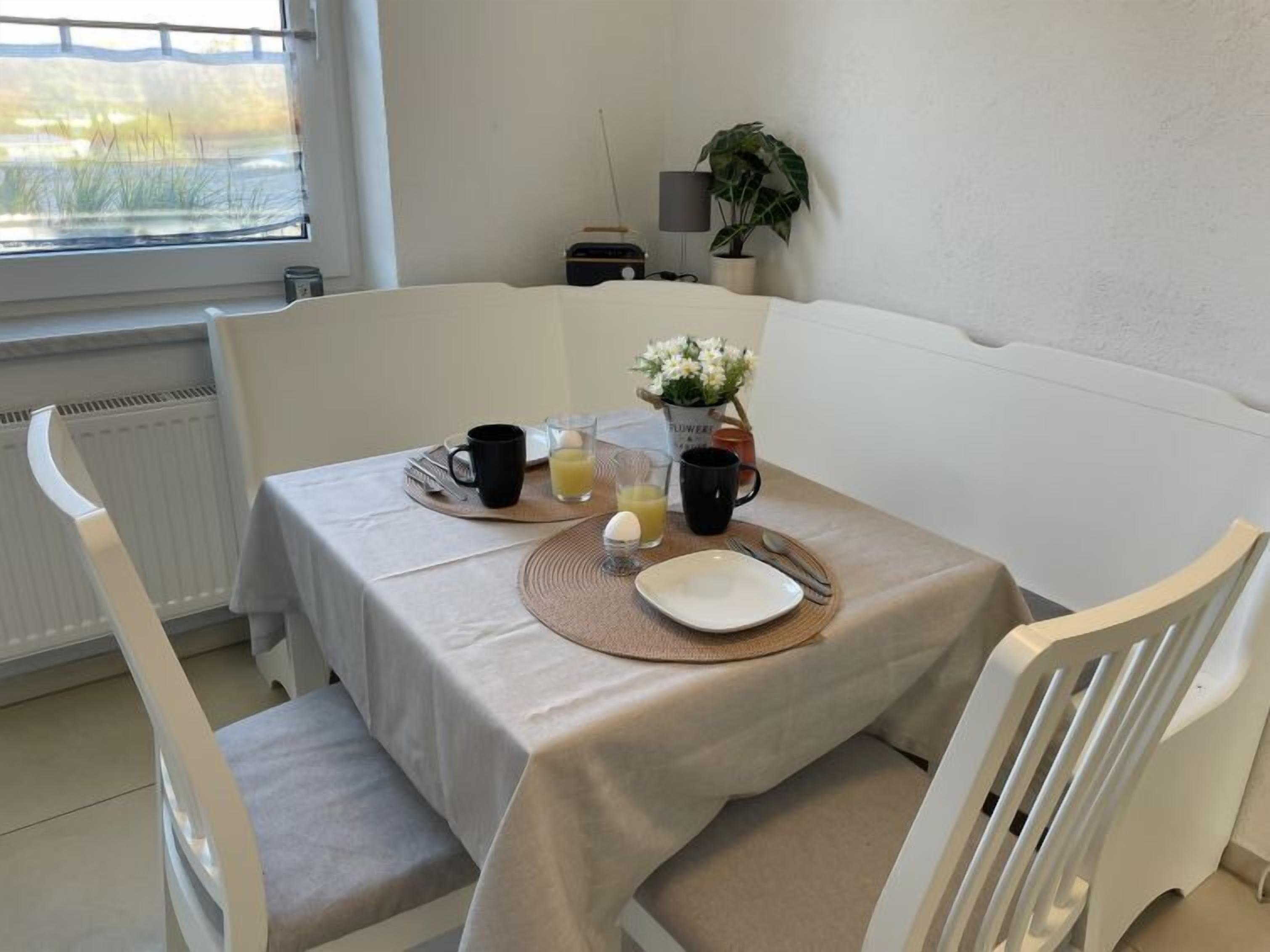 A breakfast setup with a table, chairs, and a view of a window.