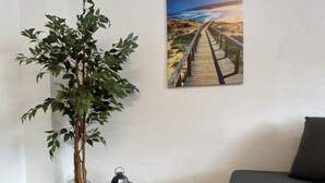 Una habitación con una planta en maceta, un farol y un cuadro de una playa.