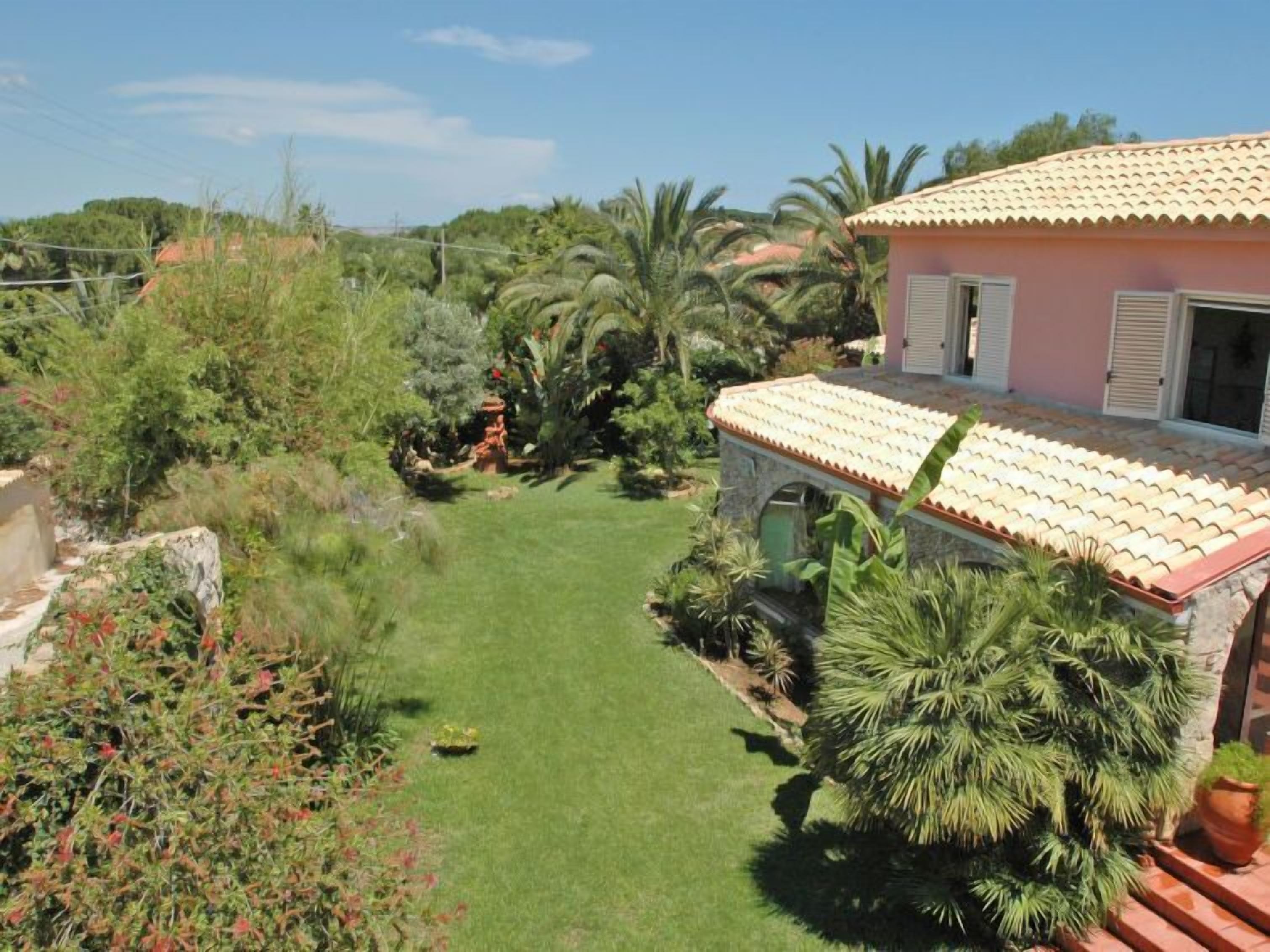A house with a tiled roof, surrounded by lush greenery and a well-maintained lawn.