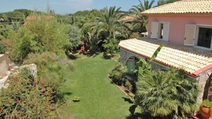 Une maison avec un toit en tuiles, entourée d’une végétation luxuriante et d’une pelouse bien entretenue.