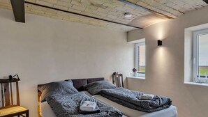 Ein Schlafzimmer mit Bett, Nachttisch, Lampe und einem Fenster mit Aussicht.