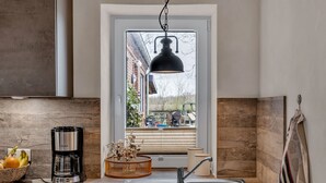 Eine moderne Küche mit großem Fenster, einer Hängelampe, einem Einbauofen und einem Spülbecken.