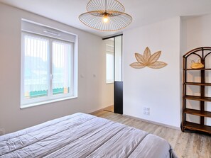 Un dormitorio con una cama, una ventana, un estante montado en la pared y una lámpara en el techo.