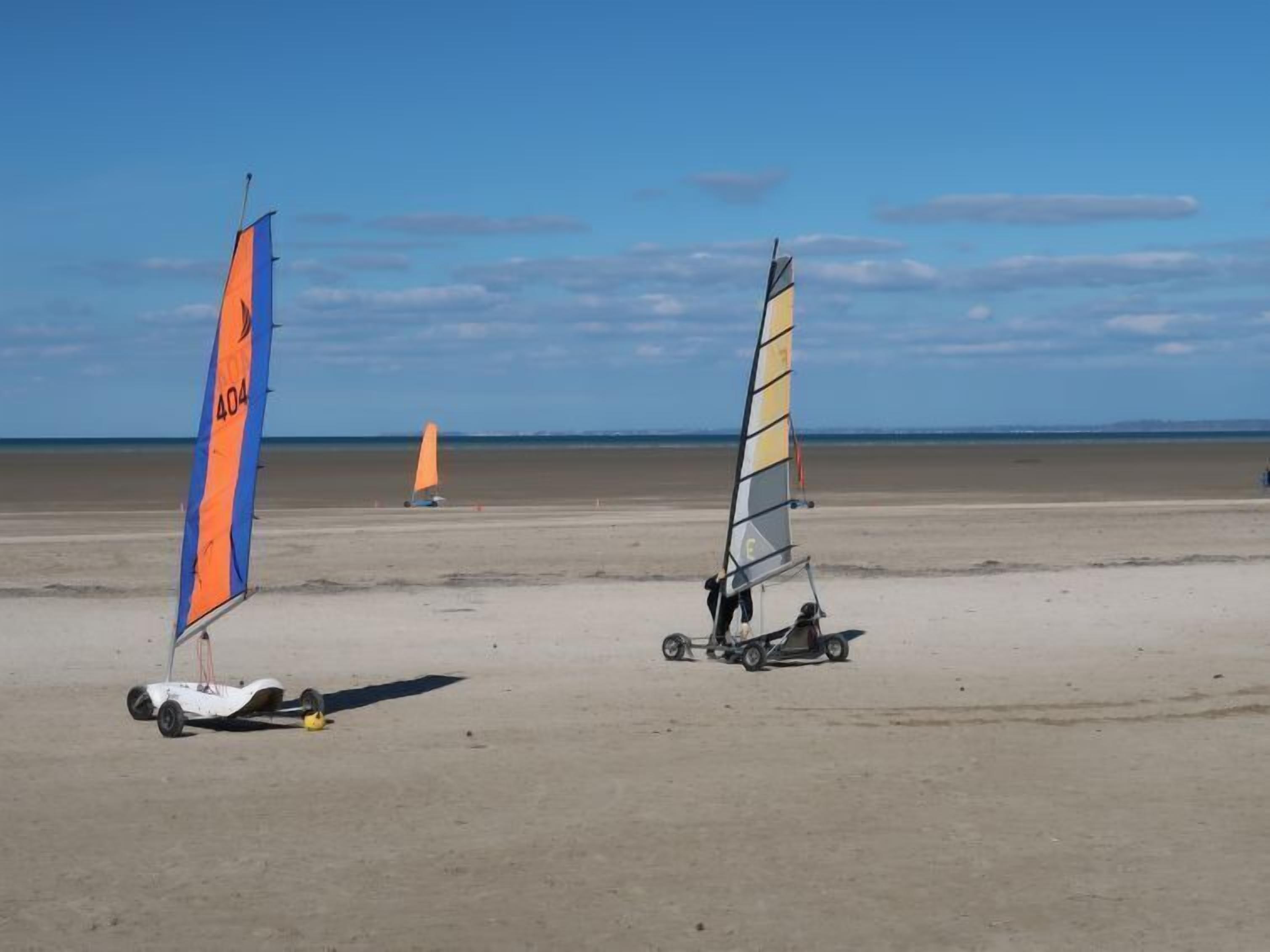 A beach with two windsurfing boards and a trailer.