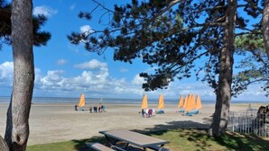 A beach with picnic tables and orange umbrellas. - l'atelier des rêves by Interhome (Cherrueix)