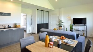 A modern living room with a sofa, dining table, and a TV. - l'atelier des rêves by Interhome (Cherrueix)