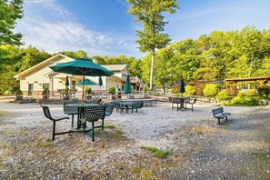 A gravel patio with outdoor seating, including tables and chairs, and umbrellas. - Lakefront, Hot Tub, Dog Friendly, Resort Amenities (Gouldsboro)
