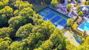 Ein Luftbild einer Anlage mit mehreren Tennisplätzen, einem Schwimmbad und einem Clubhaus.