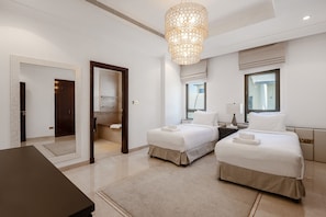 A hotel room with two beds, a large mirror, a chandelier, and a view of the outside.