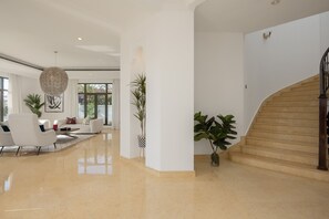 A spacious, well-lit lobby with a polished floor, a staircase, and modern furnishings.
