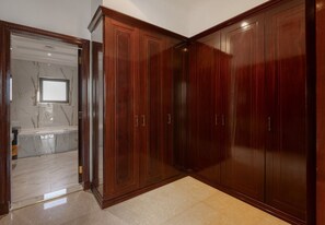 Ein Zimmer mit großem Holzschrank, Marmorboden und einem sichtbaren Badezimmer mit Marmorwaschbecken.