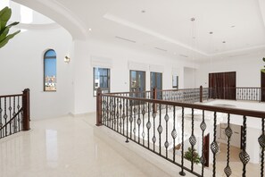 Un interior espacioso y luminoso con piso pulido, un balcón con barandilla de hierro forjado y ventanas amplias que ofrecen vistas al exterior.