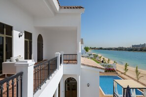 A balcony with a view of a beach and a pool.