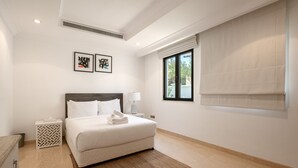 A bedroom with a bed, a nightstand, a lamp, a window with a view, and two framed pictures on the wall. - Villa on Beach w/ Private Pool The Palm Jumeirah (Dubai)