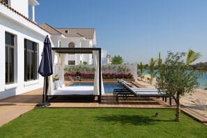 A poolside area with a lounge chair, a small table, and a pergola with a canopy.