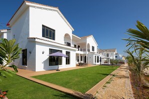 A white two-story house with a balcony, a lawn, and a pathway leading to the entrance. - Villa on Beach w/ Private Pool The Palm Jumeirah (Dubai)