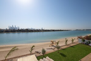 A beachfront property with a city skyline in the background, a sandy beach, and a playground.