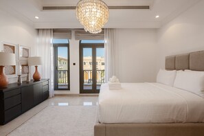 Una habitación de hotel moderna con una cama grande, un aparador de madera oscura y una araña.
