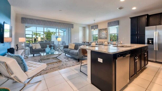 A modern kitchen with a central island, a dining area with a sofa and coffee table, and a living room with a couch and TV. - Private Pool Oasis, Solara Resort,  Stylish Decor (Kissimmee)