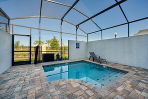 An indoor swimming pool with a clear view of the outside, a covered patio area, and a lounge chair. - Renovated Chic 5BR, Pool, Game and Themed Rooms (Kissimmee)