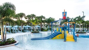 A pool area with a water slide, lounge chairs, and palm trees. - Private Pool Oasis, Solara Resort,  Stylish Decor (Kissimmee)