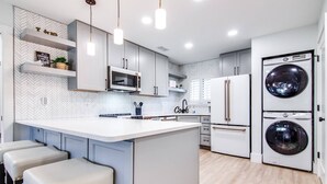 A modern kitchen with a central island, built-in appliances, and a large washing machine.