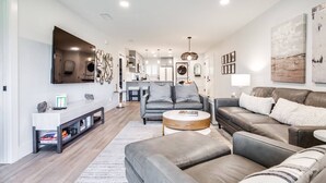 A modern living room with a grey sofa, a coffee table, and a TV mounted on the wall.