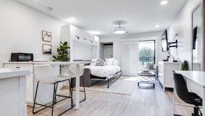 A modern, well-lit bedroom with a bed, bedside tables, and a large window.