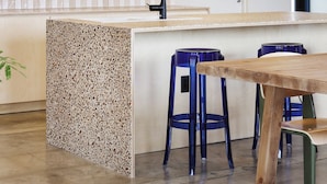 Una cocina moderna con una isla central, taburetes de bar e iluminación colgante.