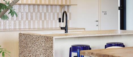 Una cocina moderna con una isla central, taburetes de bar e iluminación colgante.