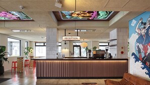 Un área de recepción moderna con mostrador, taburetes rojos y un gran mural.