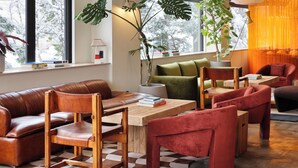 Una sala moderna con un sofá de cuero marrón, sillas de madera, una mesa de centro de madera y un sillón de terciopelo rojo.