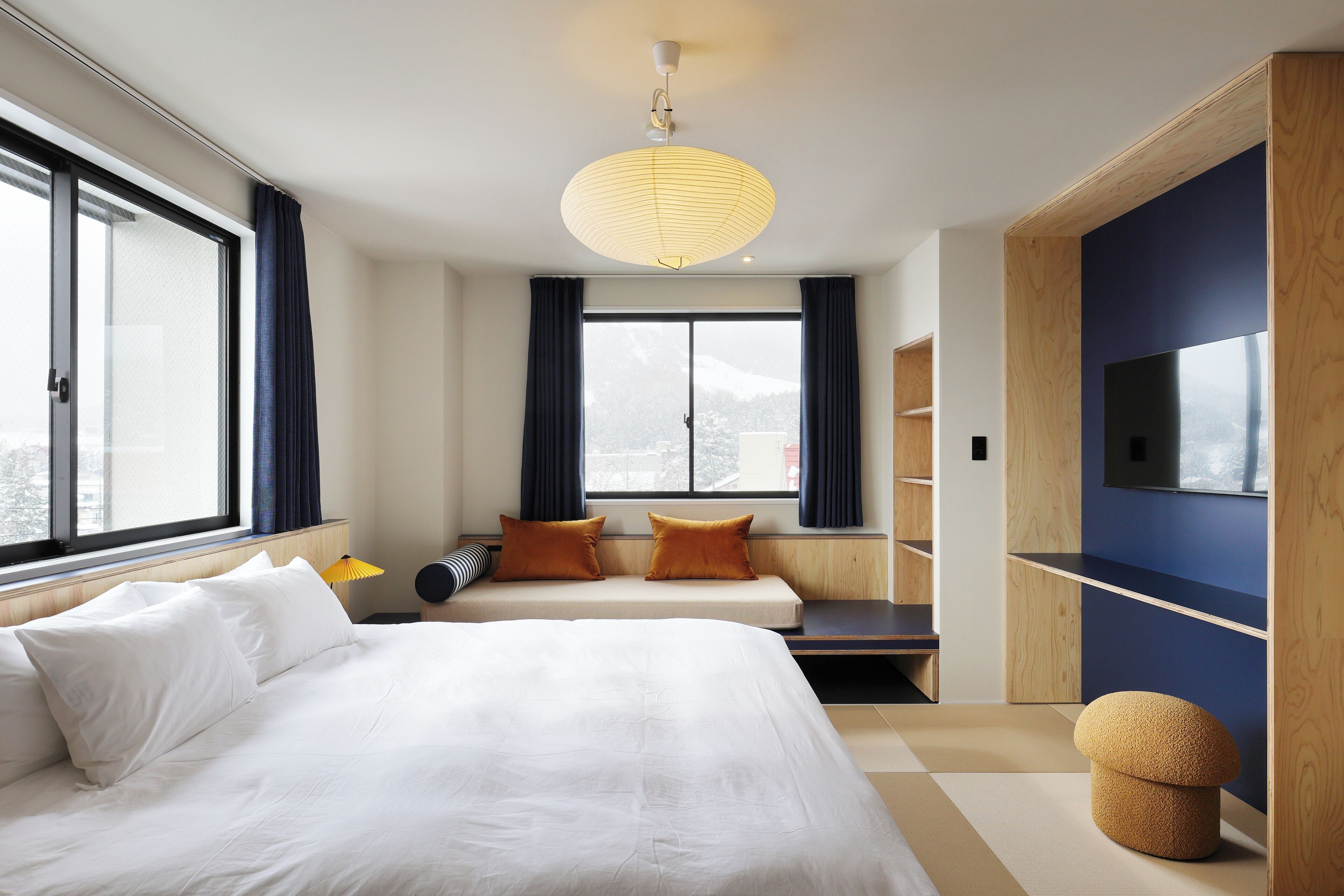 Una habitación de hotel moderna con una cama grande, un sofá, un televisor y vistas a las montañas.