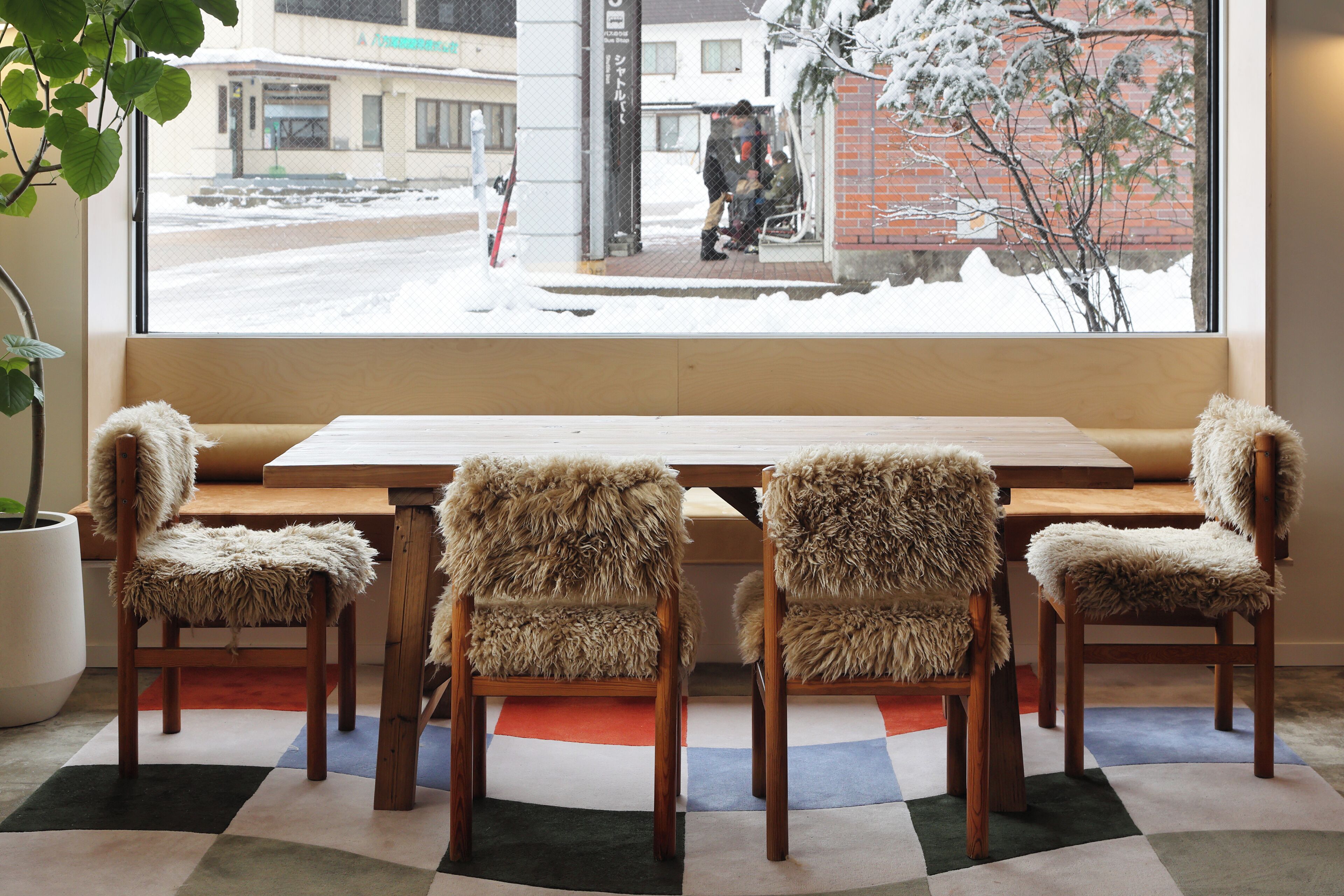 Une pièce avec une grande fenêtre, une table en bois et quatre fauteuils confortables.