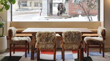 A room with a large window, a wooden table, and four furry chairs.