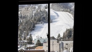 Vista a través de una ventana de un paisaje nevado con edificios y árboles.