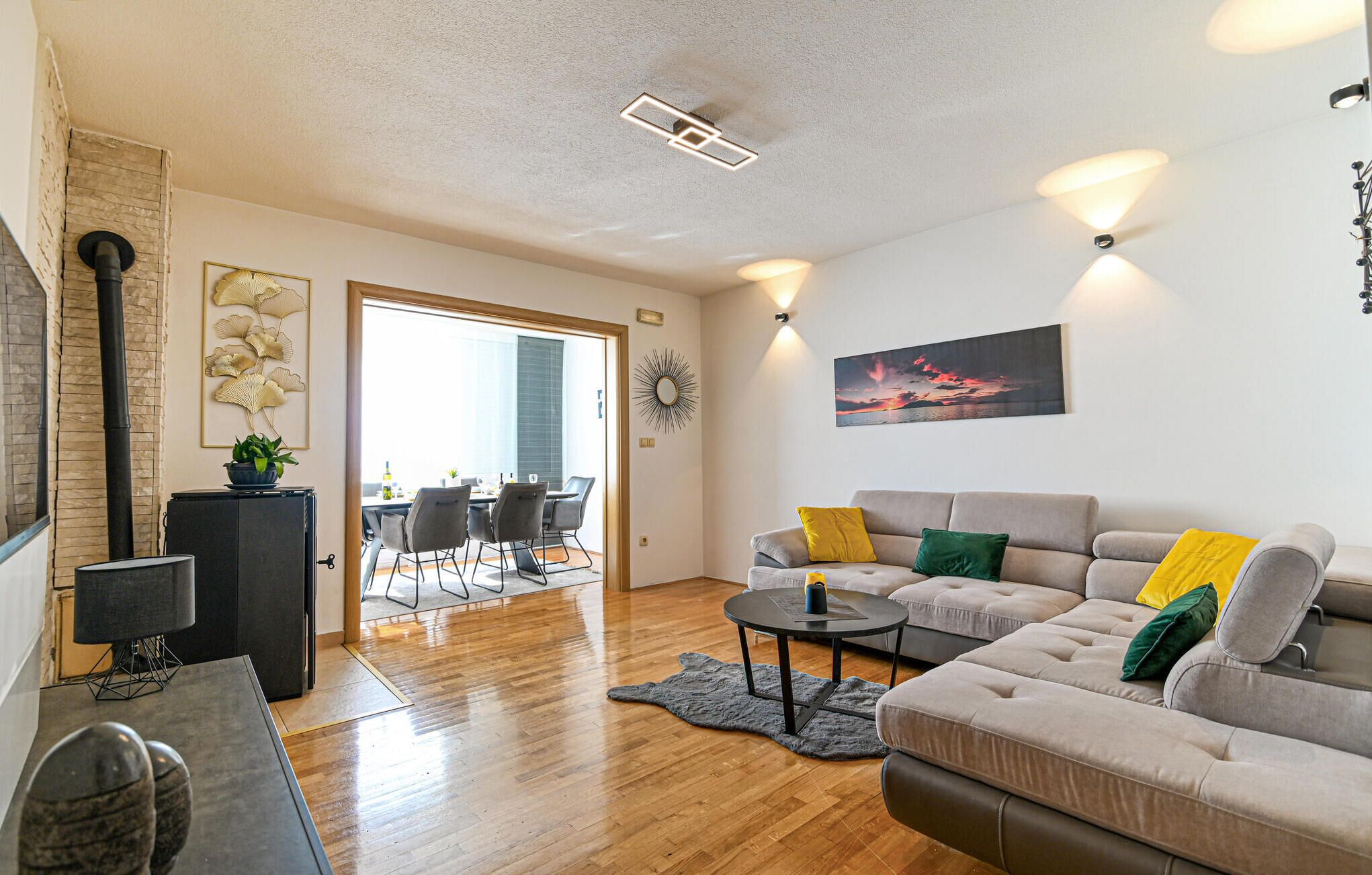 Ein modernes Wohnzimmer mit einem grauen Sofa, einem Couchtisch und einem Essbereich mit Stühlen und einem Tisch.