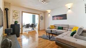 A modern living room with a grey sofa, a coffee table, and a dining area with chairs and a table. - Awesome apartment in Okrug Gornji with WiFi (Okrug Gornji)