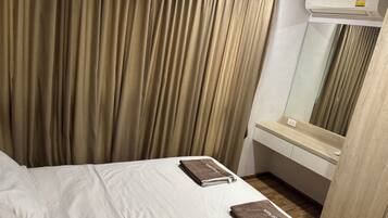 A hotel room with a bed, a mirror, and an air conditioning unit.