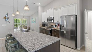Eine moderne Küche mit Granit Arbeitsplatten, Edelstahlgeräten und Pendelleuchten.