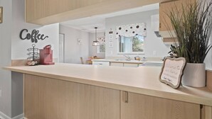 A modern kitchen with a wooden countertop, a coffee station, and a welcome sign.