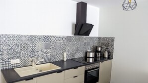 Een kleine keuken met een spoelbak, fornuis en koffiezetapparaat.