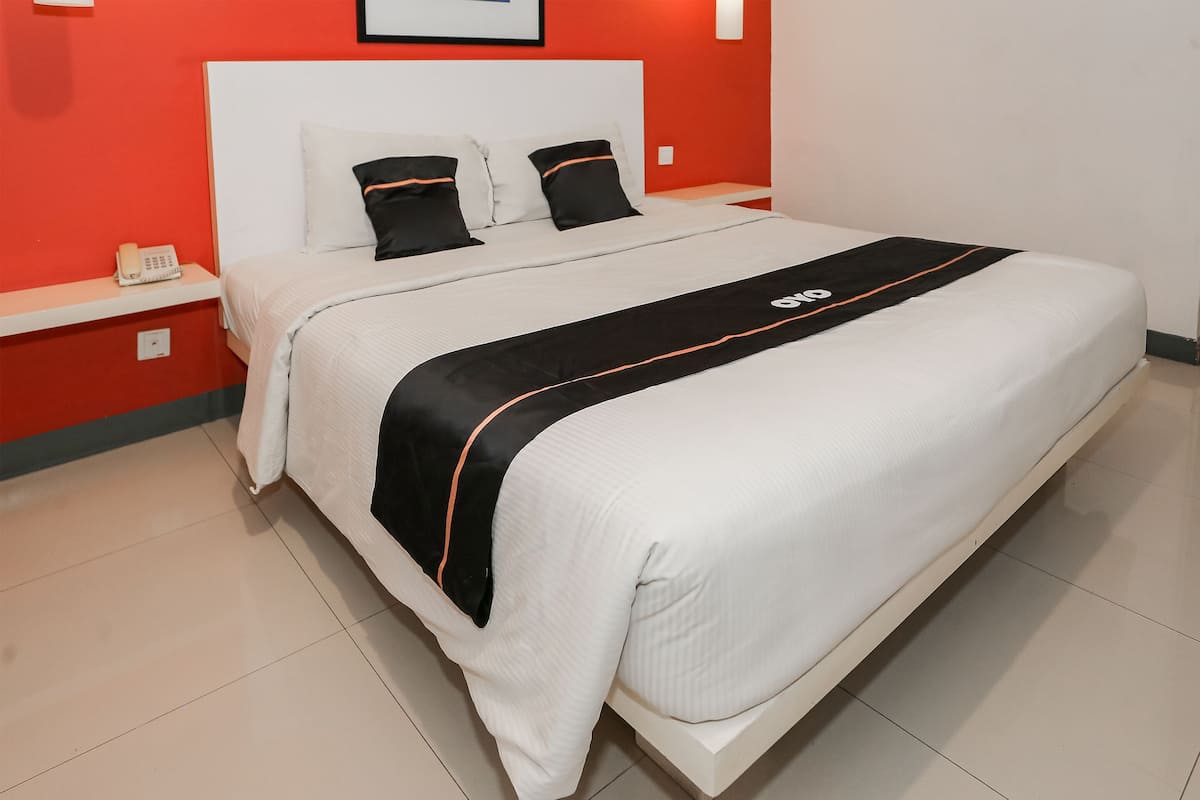 Una cama bien hecha con una colcha blanca y negra, un cabecero blanco y dos almohadas negras.