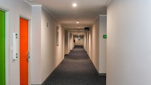 A hotel hallway with a carpeted floor, white walls, and doors numbered 385 and 386. - Capital O 93347 Glodok Inn By NAM Near Glodok Plaza (Jakarta)