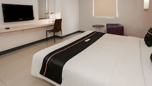 A hotel room with a bed, a desk with a chair, a TV, a small table, and a window. - Capital O 93347 Glodok Inn By NAM Near Glodok Plaza (Jakarta)