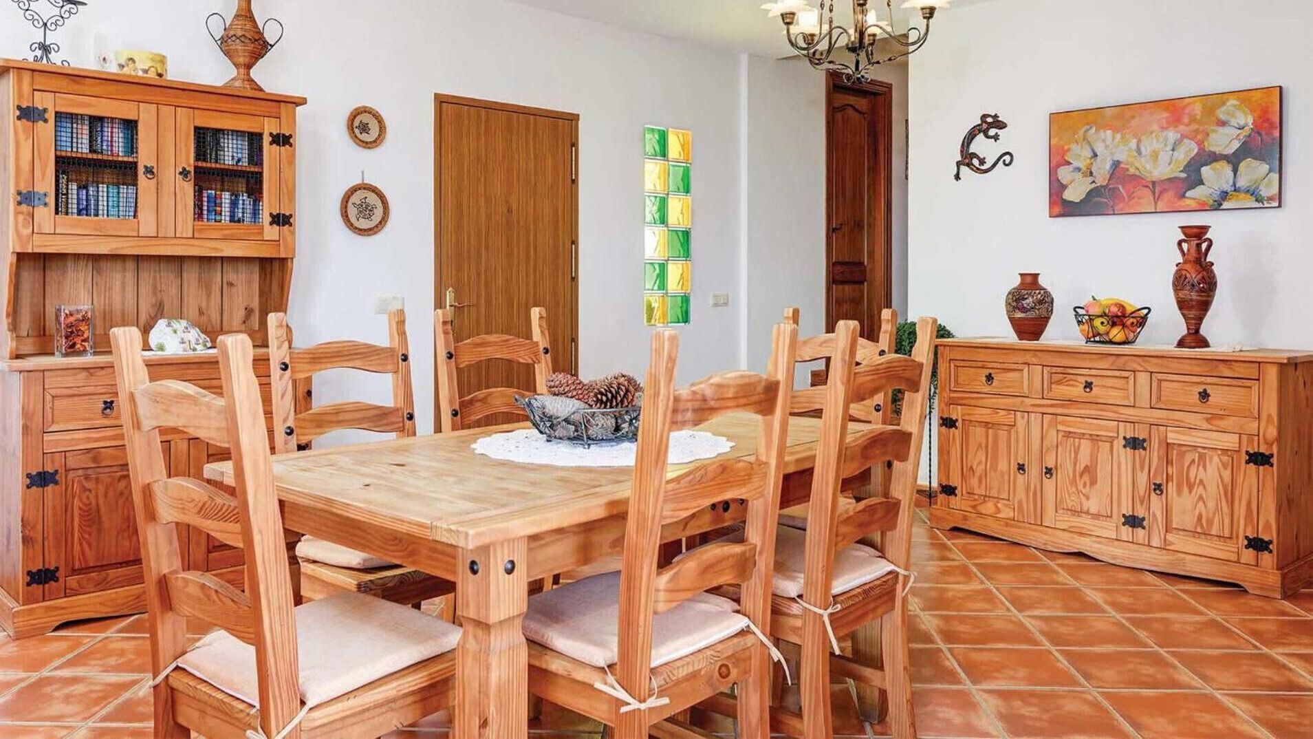 Un coin repas avec une table et des chaises en bois, un meuble avec des portes en verre et un tableau accroché au mur.
